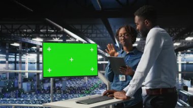 Veri merkezi mühendislik ekibi yeşil ekranda kodlanıyor, yapay zeka sistemlerini izliyorlar. Sunucu merkezi bilişim çalışanları, derin öğrenme süreçlerine ve kamera A 'ya güç veren sırt çantalarını denetlemek için model bilgisayar kullanırlar.