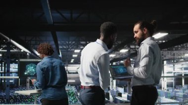 Veri Merkezi çalışanları iş birliği yapıyor, yapay zeka işleme görevleriyle ilgilenen tırların bakımını yapıyor. Sunucu merkezi yöneticileri beyin fırtınası yapıyor, derin öğrenme teknolojisini destekleyen depolama dizilerini yönetiyor, kamera A