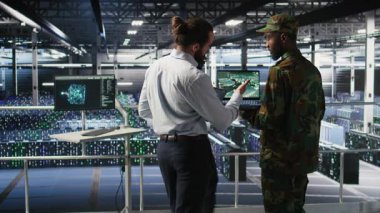 Veri merkezindeki askeri uzmanlar bilgisayardaki İHA görüntülerini inceliyor. Ordu birimleri yüksek teknoloji sunucu odasında savaş alanı keşif operasyonları yapıyor. Not defteri, kamera A kullanarak.