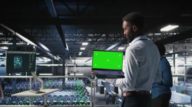 Endüstriyel platformdaki veri merkezi programcıları yeşil ekran dizüstü bilgisayar kullanarak görevlerde işbirliği yapıyorlar. Sunucu merkezi çalışanları büyük dil model mimarisini maket defteri ve bilgisayar kullanarak görselleştiriyor