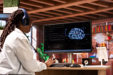 Serbest çalışan bilgisayar mühendisi yapay zeka sistemlerinde bakım yapıyor, müzik dinliyor. Uzaktan kumanda uzmanı kulaklık takıyor, yapay zeka sistemlerini kontrol ediyor.