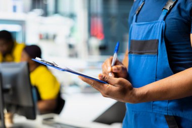 Fotovoltaik fabrikasındaki arızalı sistemleri inceleyen teknisyen parametreleri bilgisayar ve dosyalarla karşılaştırıyor. Güneş panelleri üretim tesisi ve yüksek teknoloji araştırması yapan siyah bir çalışan..