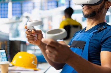 Siyah endüstriyel fabrika çalışanı sistem performansını denetlemek için sanal gerçeklik teçhizatı kullanıyor. Güneş panelleri imalat fabrikası teknisyeni enerji üretimini izlemek için VR gözlükleri kullanıyor.