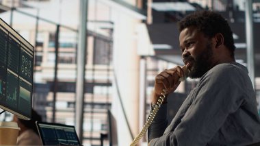 Afrika kökenli Amerikalı bir uzman sabit bir telefon görüşmesinde masasında fon görüşmeleri, genişleme projesini yönetmek ve büyüme stratejilerini tartışmak. CEO kariyer başarısı için birden fazla iş yapıyor. Kamera A.