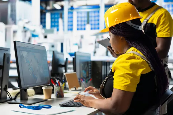 Fotovoltaik fabrikasındaki teknisyenler güneş panelleri montaj hatlarını inceliyor, sanayi yönergelerini okuyor ve sorunsuz üretim sağlıyorlar. Tüm siyah takımlar güneş pili etkinliğini optimize ediyor..