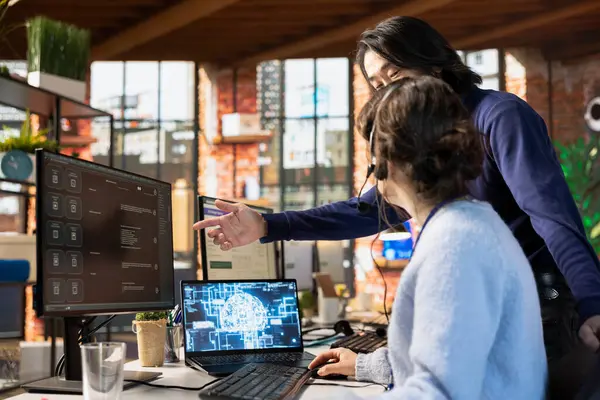 Çağrı Merkezi Müdürü, AI Chatbot 'un bilgisayar masasında nasıl kullanılacağı konusunda stajyere rehberlik ediyor. Asyalı müşteri desteği uzmanları kadınlara yapay zeka yazılımı kullanmayı öğretiyor.