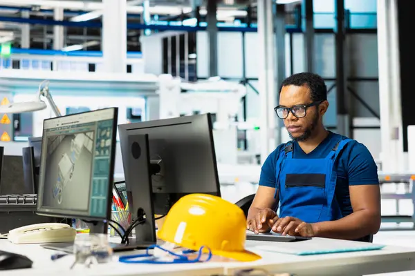 Güneş enerjisi fabrikasındaki enerji tüketim yazılımını analiz eden Afrikalı Amerikalı teknisyen, güneş pillerinin üretimini arttırmak ve otomatik makine sistemlerindeki teknik sorunları azaltmak için PC programını kullanıyor..