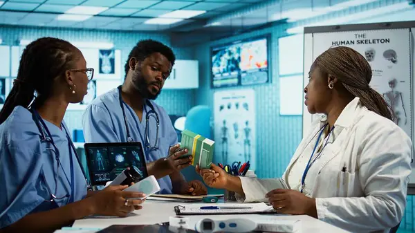 Önlüklü erkek ve kadın hemşireler uzman doktor, bakım yönetimi ile profesyonel eğitim ve araştırma yapmaktadırlar. Sıhhiye onlara ilaç ve ilaç stoğu sunuyor. Kamera B.