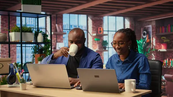 Siyah adam ve kadın rahat dairelerinde oturup dizüstü bilgisayarda dijital pazarlama stratejisini tartışıyorlar. Birbirlerine uzak işlerinde ve serbest yolculuklarında destek oluyorlar. Kamera A.