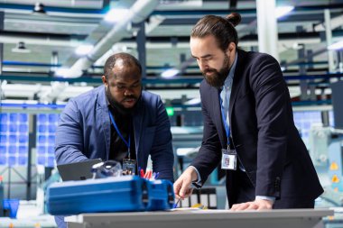 Çok ırklı iş ortakları ve mühendisler, sürdürülebilir enerji ve sanayi operasyonlarında gelecekteki gelişmeleri planlayan bir güneş teknolojisi üretim tesisinde bir tartışma için bir araya geldiler..