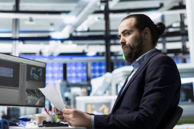 Bir güneş paneli tesisinde erkek inşaat müteahhiti rutin bir teftiş gerçekleştirir, yenilenebilir enerji gelişimine katkıda bulunur ve mühendislik süreçlerinde yüksek standartları sürdürür..
