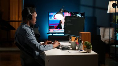 Genç programcı mühendis terminal penceresine ikili kod verileri yazıyor, ev düzeninde serbest çalışıyor. Yazılım geliştiricisi programlama dili ile sorun çözme üzerine çalışıyor. Kamera B.
