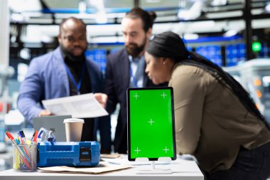 Takım elbiseli ekip üyeleri yeşil ekranın yanındaki fabrika faaliyetlerini denetliyor, sürdürülebilir endüstriyel enerji dünyasındaki profesyonellik ve teknik uzmanlığı harmanlıyor. Ucuz güç..