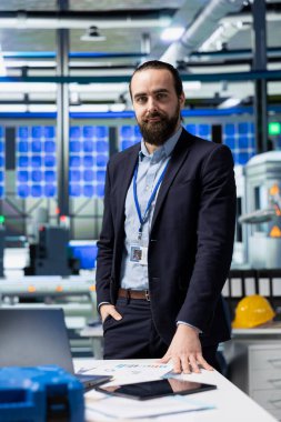 Üretim analisti, yüksek teknolojili endüstriyel bir ortamda, teknolojik hassasiyet ve sürdürülebilir enerji geliştirme üzerine odaklanarak, güneş paneli üretim iş akışını gözden geçiriyor..