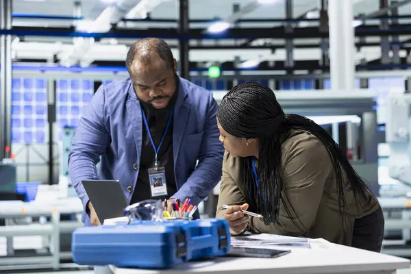 Siyah endüstri mühendisleri üretim denetimi sırasında güneş paneli sistemleri üzerinde birlikte çalışarak mühendislik doğruluğu, kalite kontrolü ve fabrika işletim verimliliğini sağlıyorlar..