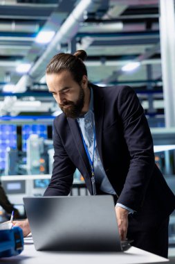 Resmi kıyafet giymiş genel müdür bir güneş paneli fabrikasında teftiş yapıyor. Yeşil enerji endüstrisindeki modern altyapı ve liderliği sembolize ediyor. Üretim planlama ve teknoloji.