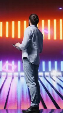 Dikey video gündelik genç adam parlak neon ışıklara canlı renklerle bakıyor, fütürist siber punk atmosferinin tadını çıkarıyor. Bir gece sahnesinde kentsel tarz ve yaratıcılık gösteriliyor