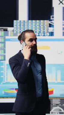 Vertical Video Professional işadamı, şirketin performansını ve sezgilerini değerlendirmek için KPI metrikleriyle çevrili bir telefon görüşmesine cevap veriyor. İşini geliştirmek için uzaktan iletişimi kullanıyor.