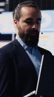 Dikey Video Erkek konuşmacı ve iş koçu canlı seyircilerle dinamik bir sunum yapıyor. Teknoloji güdümlü bir iş etkinliğinde paylaşım stratejisi, büyüme fikirleri ve mali tahminler