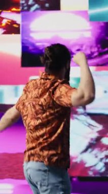 Dikey Video Cool dijital içerik yaratıcısı parlayan neon ışıkların altında dans ediyor, ritim ve bireyselliği ifade ediyor. Modaya uygun müzik ve sanatsal görsellerle çevrili, enerji ve retro stil getiriyor.