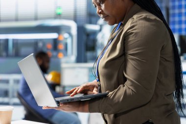 Siyah alternatif enerji danışmanı, bir güneş enerjisi santralinde fabrika uygulamalarının yeşil enerji hedeflerine ulaşmasını sağlayarak operasyonları gözlemliyor. Uzman verimlilik üretmek için dizüstü bilgisayar kullanıyor.