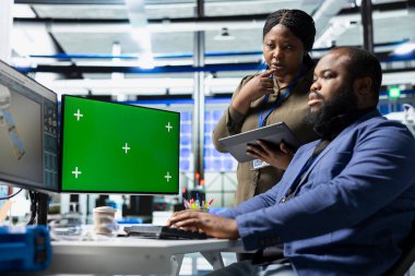 Krom anahtarın yanındaki güneş panellerini inceleyen siyah mühendislik ekibi yeşil teknoloji ve çevre dostu yenilenebilir enerjide birlik gösteriyor. Üretim endüstrisinde operasyonel liderlik.