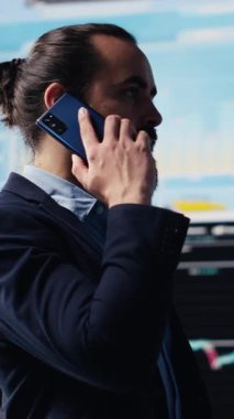 Dikey Video Erkek Girişimcisi KPI ölçümleri hakkında bilgi paylaşmak ve şirket performansını değerlendirmek için bir telefon görüşmesi yapıyor. Uzman, kazancını arttırmak için uzaktan iletişim kullanıyor.