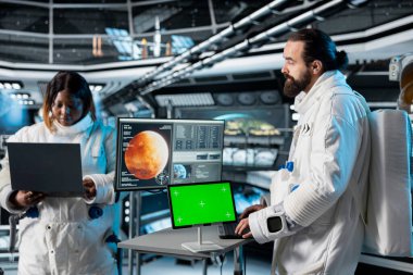 Astronot Mars 'a inmeden önce yeşil ekran tablet arayüzünü kontrol ediyor. Kızıl Gezegen yüzeyindeki görev sırasında krom anahtar cihaza bakan mürettebat üyeleri uzayın derinliklerinde insan yaşamını test ediyorlar.