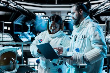 Kozmonotlardan oluşan bir ekip dizüstü bilgisayarda uzaktan ölçüm yazılımı çalıştırıyor ve dışarıdaki gezegen görevine hazırlanıyor. Astronotlar roket iticilerini kontrol ediyor, defter kullanarak, gezegene iniş prosedürlerini başlatıyorlar.