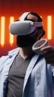 Dikey Video Genç havalı insan VR teknoloji aletleriyle neon ışıkların altında eğleniyor, siber punk tarzını somutlaştırıyor ve sanatsal bir vizyon için renkli bir ilham kaynağı. Estetiğin parıldayan yansımaları