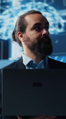 Dikey Video Erkek İş Adamı Yapay Zeka Stratejisi ve Otomasyon Aletleri üzerine çalışıyor. Veri görselleştirmesi, sinirsel ağlar ve bulut hesaplamalarıyla çevrili olarak, akıllı teknolojiyi keşfeder.
