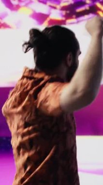 Dikey Video Cool dijital içerik yaratıcısı parlayan neon ışıkların altında dans ediyor, ritim ve bireyselliği ifade ediyor. Modaya uygun müzik ve sanatsal görsellerle çevrili, enerji ve retro stil getiriyor.