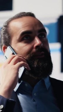 Vertical Video Professional işadamı, şirketin performansını ve sezgilerini değerlendirmek için KPI metrikleriyle çevrili bir telefon görüşmesine cevap veriyor. İşini geliştirmek için uzaktan iletişimi kullanıyor.