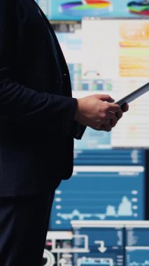 Vertical Video Professional işadamı dijital torpido gözündeki bilgi ve finans grafiklerini analiz ederek tablette bilgi grafikleriyle stratejik planlamayı güvence altına alıyor. Hızlı kurumsal ekonomide liderlik
