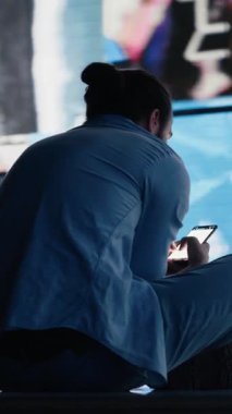 Dikey Video Umutsuz Adam, sefalet içinde telefon ekranına bakıyor. Aşırı toksik sosyal medya kullanımını simgeliyor. Saplantı ve aşırı bilgi, akıl sağlığı, endişe ve depresyonu etkiliyor. Kamera A