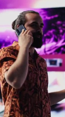 Vertical Video Artistic çalışanı ve DJ, canlı neon ışıklar, müzik kültürü, görseller ve sosyal medya veya yayın için kentsel ortam ile gece hayatı titreşimi altında telefon görüşmelerine cevap verir. Havalı yaratıcı adam.