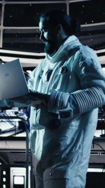 Dikey video Jolly astronot akıllı telefon kamerasıyla yıldız gemisinde selfie çekerken eğleniyor. Uzay istasyonunda kozmonot kozmik yolculuk sırasında cep telefonuyla fotoğraf çekiyor.