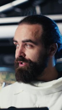 Fütürist uzay gemisinin içindeki dikey video astronot rutin görev kontrolü sırasında Kızıl Gezegen yolculuk analizlerini kontrol ediyor. Uzay istasyonu kozmonotu Mars 'ı gösteren monitörün yanında duran aygıtı kullanıyor.