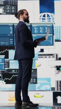 Vertical Video Visionary iş dünyası lideri kalabalık bir konuşma etkinliğinde veri ve grafikler kullanarak ayrıntılı bir iş sunumu yapıyor. CEO uzmanı olarak dinleyen izleyiciler büyüme ve başarı anlayışını paylaşıyor