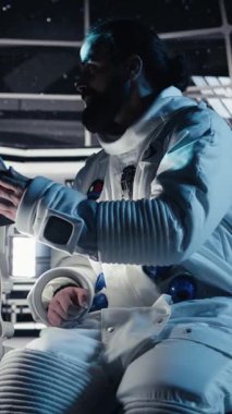 Dikey video astronot keşif görevi sırasında uzay istasyonunda akıllı telefonuyla selfie çekerken el hareketi yapıyor. Adam kozmik keşif sırasında cep telefonuyla fotoğraf çekiyor, kamera.