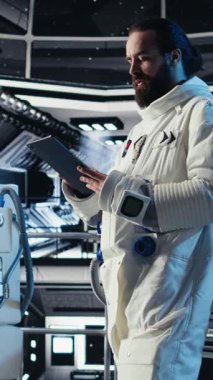 Tebessüm eden astronotun koruma kaskı tutarken uzayda insan büyümesi yaptığı dikey video portresi. Yıldız gemisindeki neşeli adam uzun vadede insanlığın kurtuluşunu destekleyen keşif gezisine hazırlanıyor.