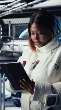 Yörünge istasyonunun dışına planlanmış operasyonlara çıkmadan önce miğfer tutan mutlu astronotun dikey video portresi. Uzay aracında gülümseyen kozmonot uzak gezegen yüzeyine yaklaşıyor.