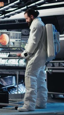 Uzay istasyonunun dışındaki planlanmış operasyonlara çıkmadan önce kaskını takan dikey video astronotu iş arkadaşıyla yumruk tokuşturuyor. Kozmonot indikten sonra uzay gemisinden ayrılmaya hazırlanıyor.