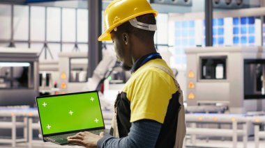 Akıllı fabrikadaki mühendis IoT sensör verilerini analiz etmek için yeşil ekran dizüstü bilgisayar kullanıyor. Endüstri 4.0 bitkisel uzmanlık sistemi tanımlaması krom tuşlu model defter üzerinde duraklama süresini azaltmak için B kamerası