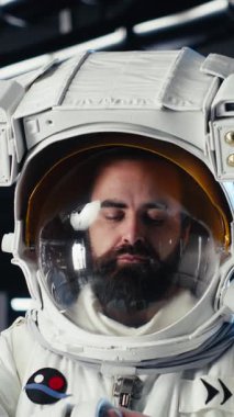 Yüksek teknolojili uzay aracının içindeki gülümseyen astronotun dikey video görüntüsü rutin görev kontrolü sırasında ekipman çantasını tutuyor. Mars verilerini gösteren mutlu bir yıldız gemisi mürettebatı ekranın yanında duruyor.