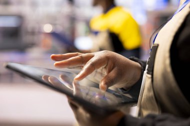Akıllı fabrika mühendisi CAD yazılımında üretim hattı düzeni geliştirmek için tablet kullanıyor. Endüstriyel zemin yapılandırmalarını dijital aletlerle optimize eden Afrikalı Amerikalı işçilere yakın çekim.
