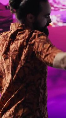 Elektronik ritimler ve sanatsal görsellerle kulüpte dans eden Dikey Video DJ etkileyicisi harika hareketler sergiliyor. Siber punk müzik kültürü ve yaratıcılığı kentsel dijital yaşam tarzını yakalar