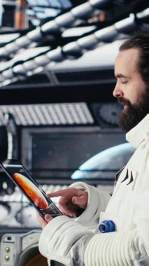 Yabancı gezegendeki yüzey görevini tamamladıktan sonra uzay istasyonu analizlerini kontrol etmek için tablet kullanan dikey video kadın astronot. Kadın navigasyon koordinatlarını giriyor, dönüş için hazırlanıyor