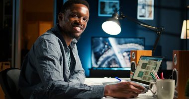 Afrikalı Amerikalı serbest yazar, evde notlar yazıyor ve veri odaklı konuları araştırıyor. Uzak çalışma başarısı için modern bir dairede verimlilik ve planlama görevlerine odaklanmış. Kamera A.