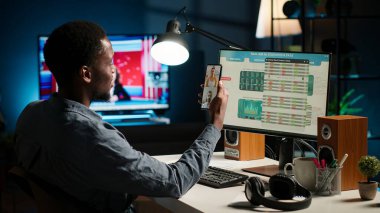 Danışmanlarla görüntülü konuşma yapan siyahi ekonomist, kazanç dengesi analizi ve potansiyel büyüme için mali dalgalanmayı izliyor. Uzman iş arkadaşlarıyla tartışıyor. Kamera B.